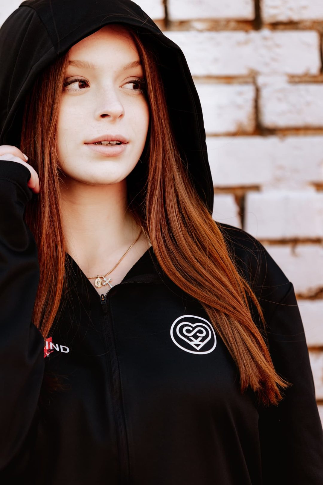 Close portrait of the hood and chest badge of a black Super Kind Company zip hoodie.
